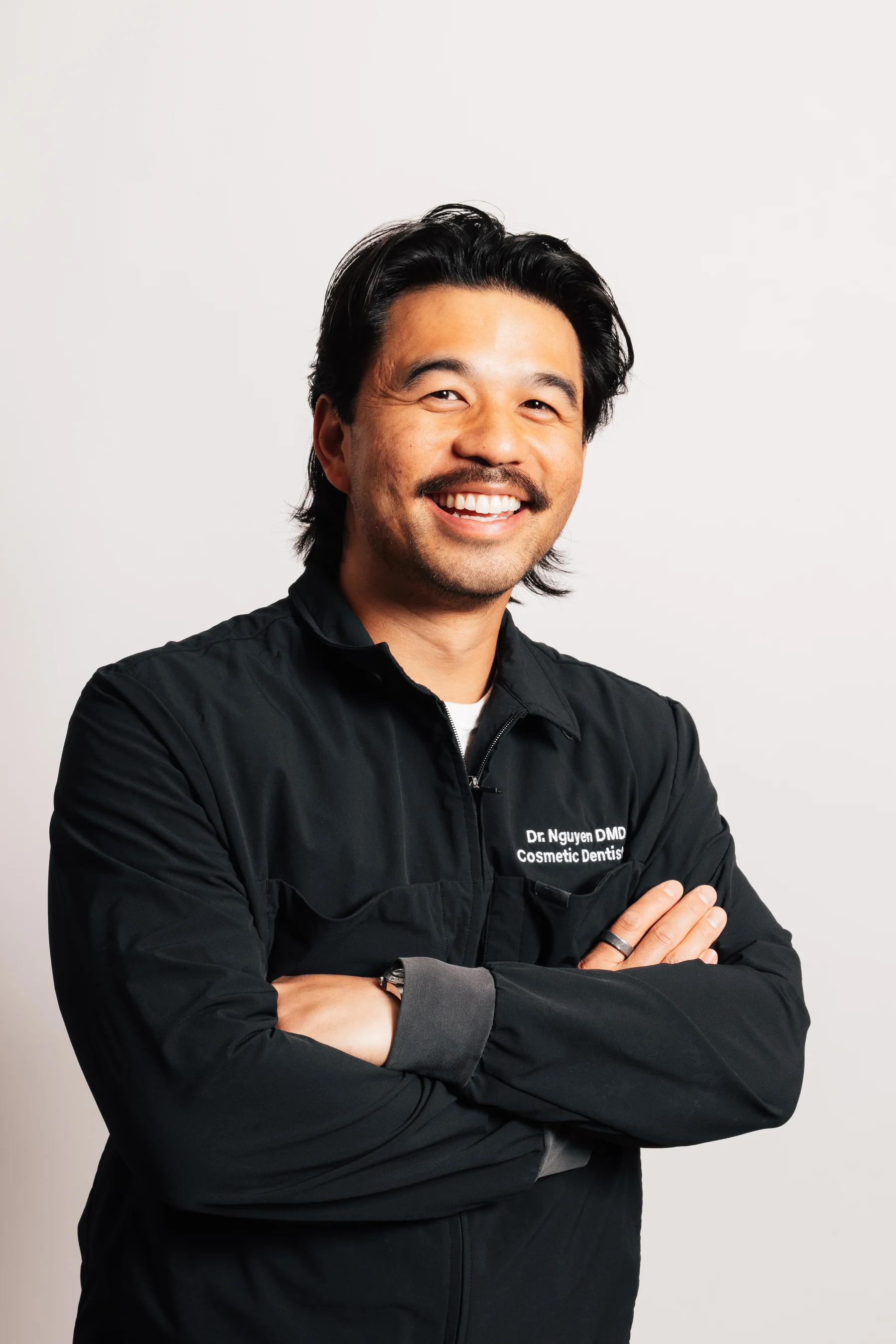 Dr. Khoa Nguyen, DMD, smiling in grey dental jacket